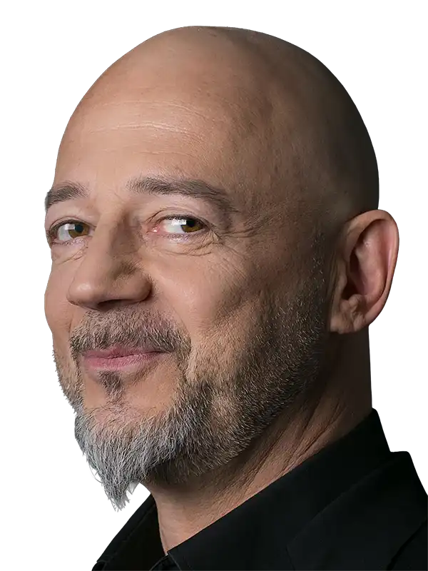 Porträt von Eleftherios Pursanidis und lächelndem Gesichtsausdruck vor dunklem Hintergrund.