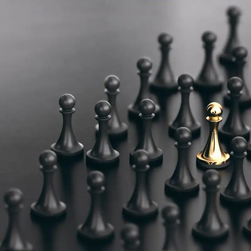 Eine goldene Schachfigur steht zwischen schwarzen Schachfiguren auf einem Tisch.